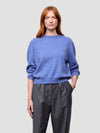 Woman wearing a blue cashmere sweater and gray pants on a light gray background