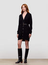 Woman wearing a long black cashmere cardigan with buttons and black knee-high boots on a white background