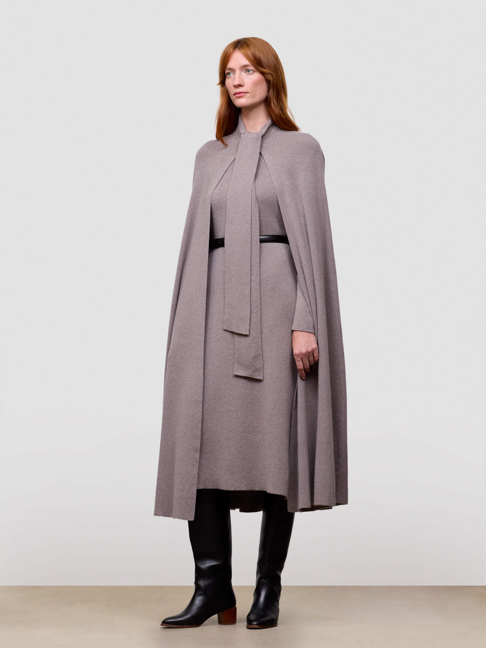Woman wearing a long gray cashmere cape with a plain background