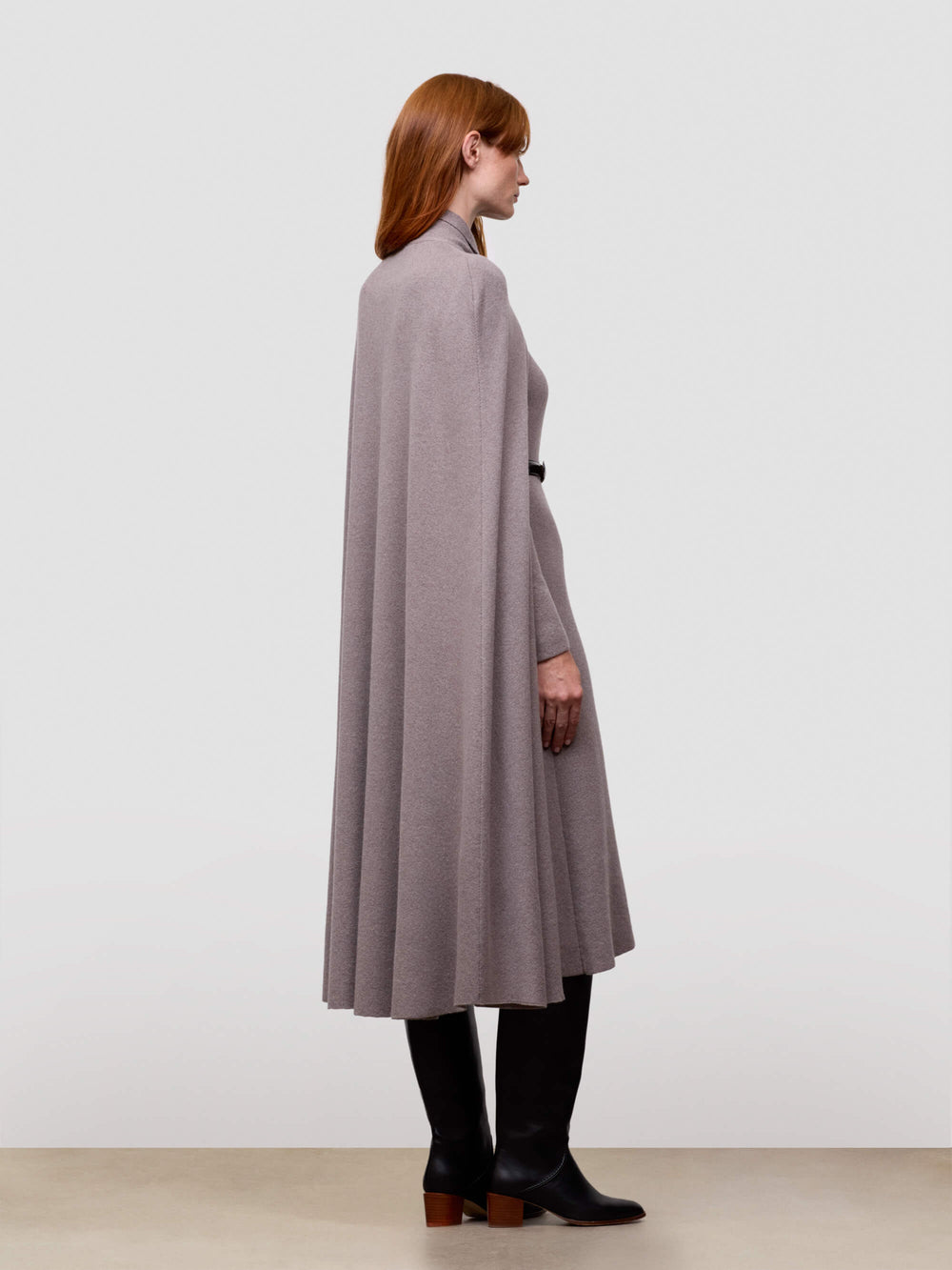 Woman wearing a long gray cashmere cape with a plain background
