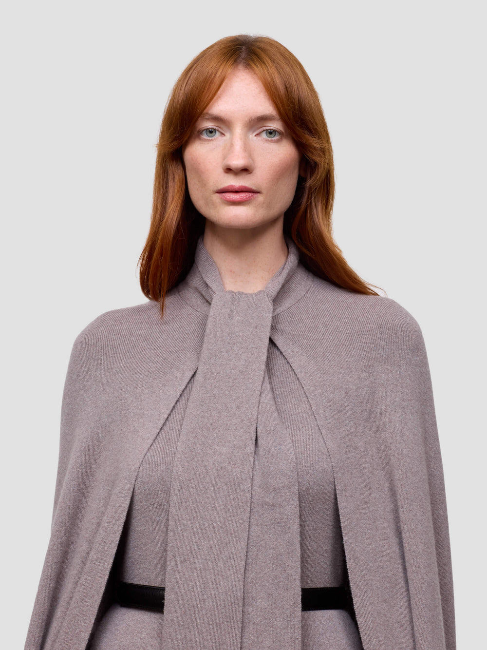 Woman wearing a gray cashmere cape against a light gray background
