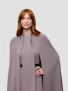 Woman wearing a long gray cashmere cape with a plain background
