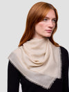 Woman wearing a beige cashmere scarf on a plain background