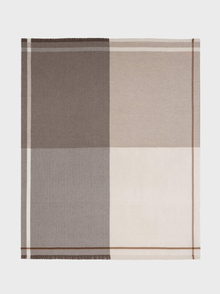 A cashmere blanket with a large-scale quad design in beige, brown, and white colors, featuring a herringbone twill texture and combed fringe.