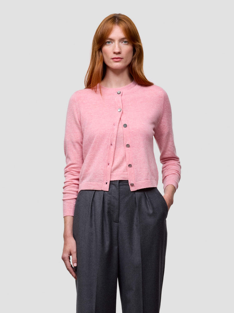 Woman wearing a pink cardigan with black buttons on a light gray