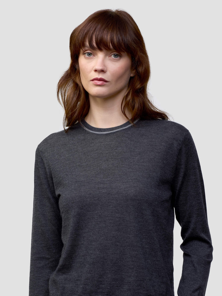 Woman wearing a dark gray cashmere sweater and light gray cashmere pants on a white background