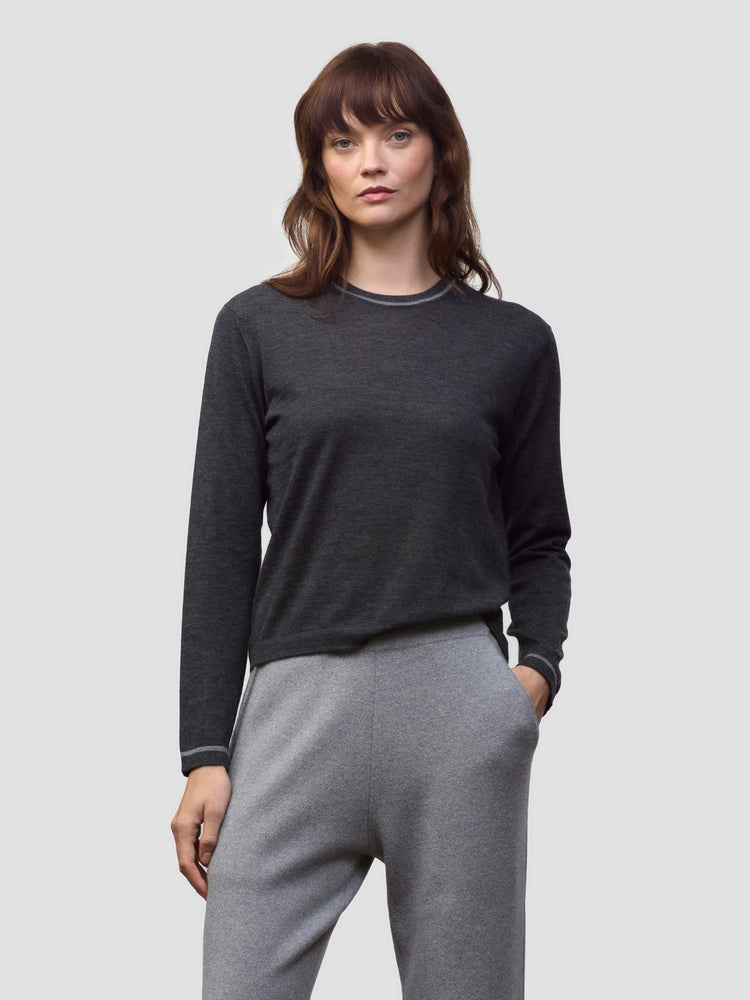 Woman wearing a dark gray cashmere sweater and light gray cashmere pants on a white background
