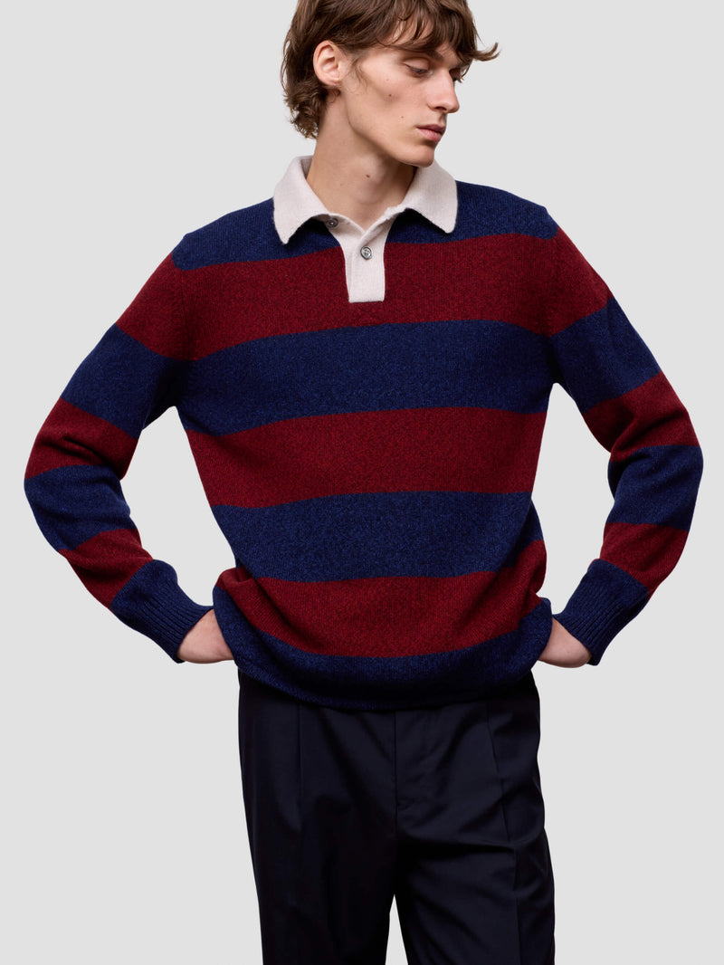 Man wearing a red and blue striped cashmere sweater over a white shirt on a light gray background