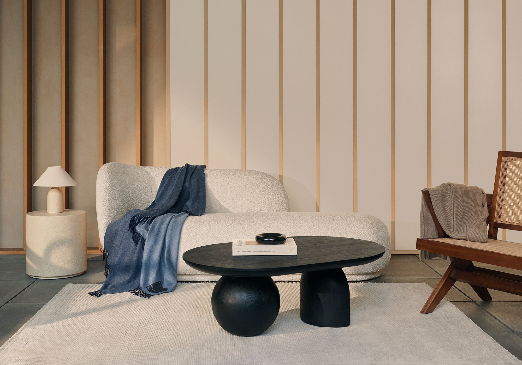 a living room with a reversible blue and dark blue cashmere throw draped on a beige boucle sofa