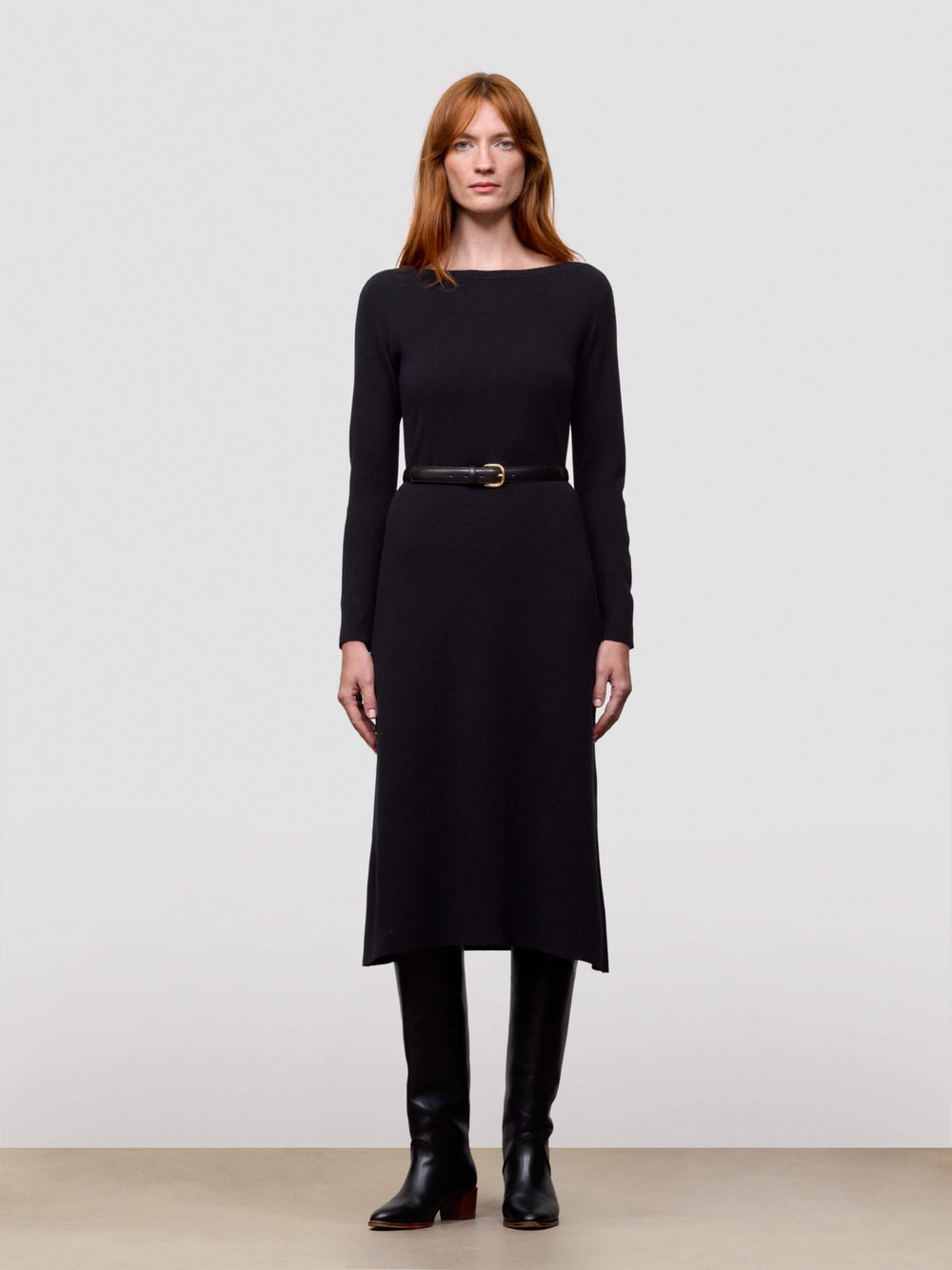 woman wearing black cashmere dress and boots on a plain background