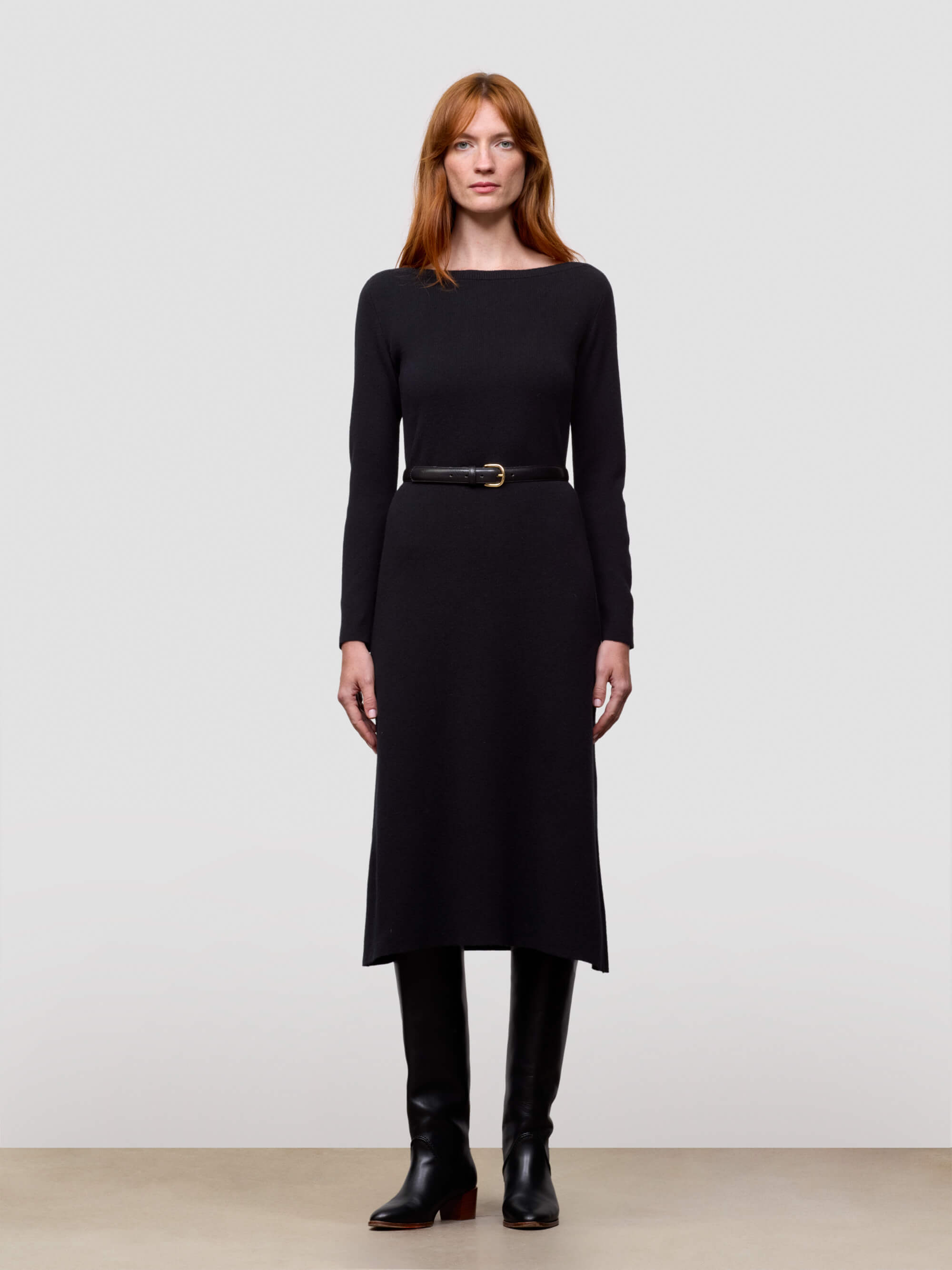 woman wearing black cashmere dress and boots on a plain background