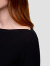 woman wearing a black sweater with a neutral background