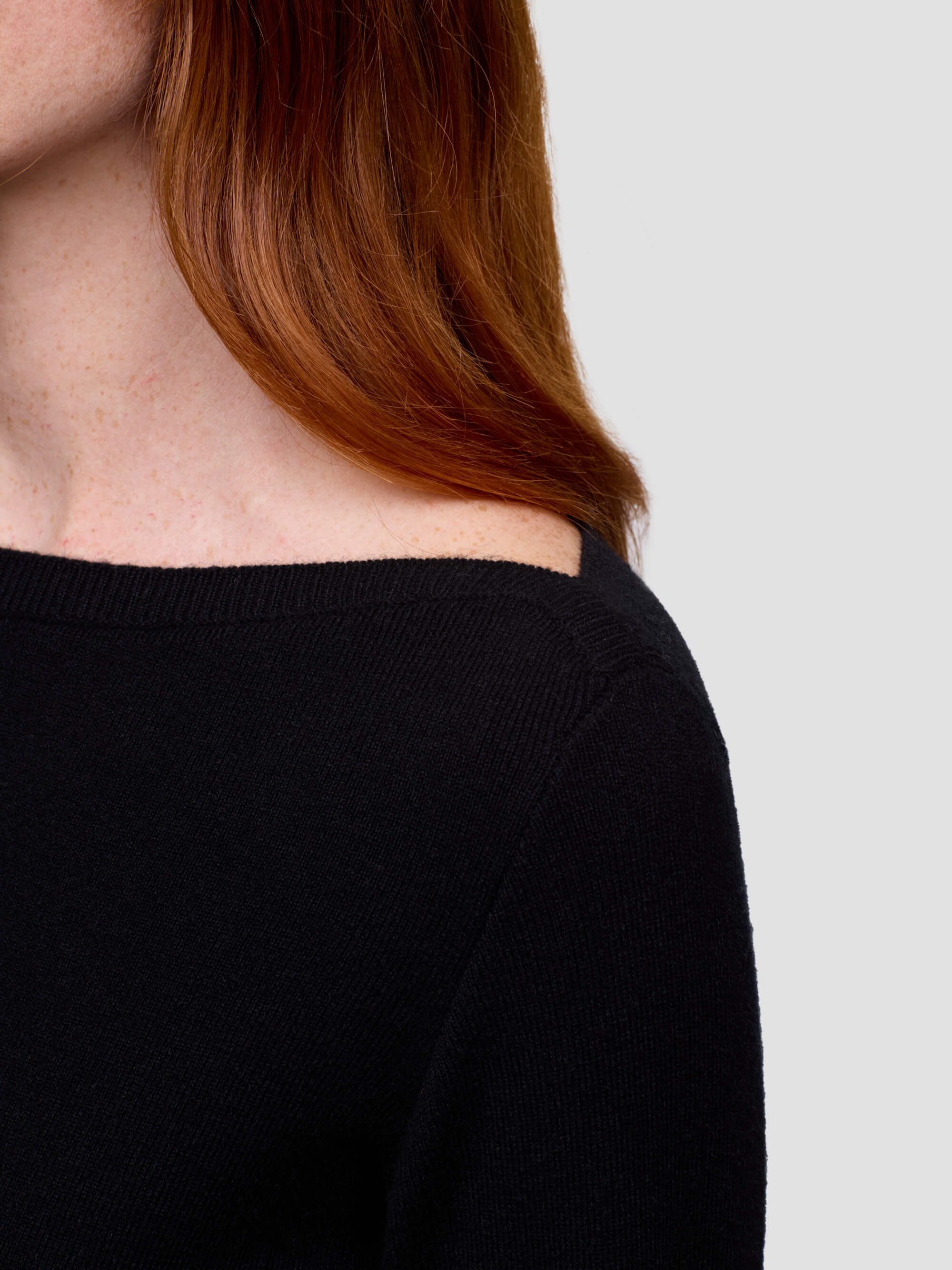 woman wearing a black sweater with a neutral background