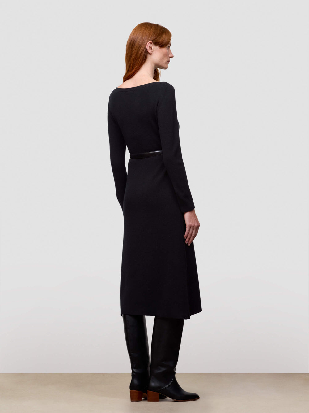 Woman wearing a black cashmere dress with a plain background