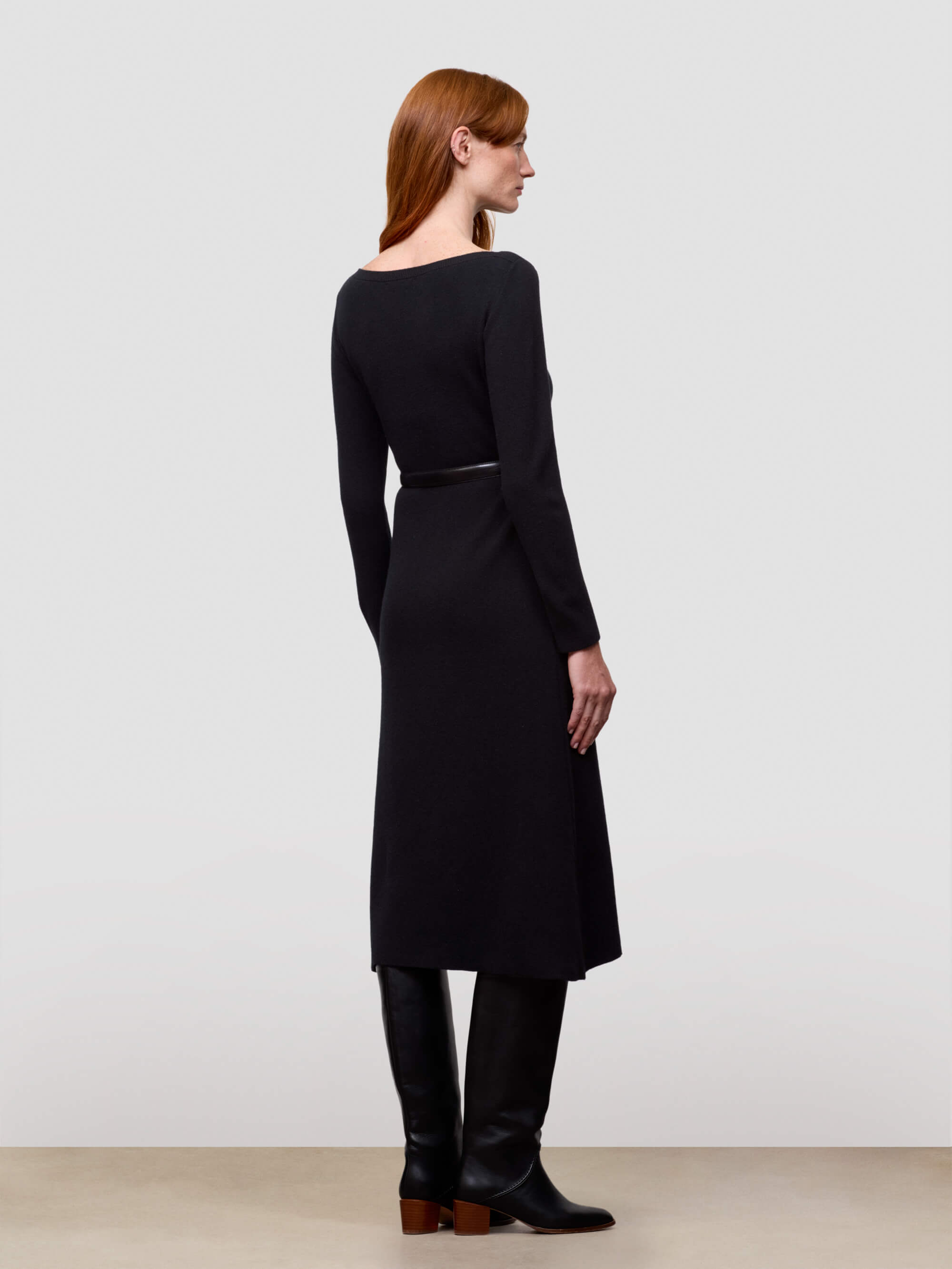 Woman wearing a black cashmere dress with a plain background