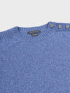 denim blue cashmere crew neck sweater with pearl button shoulder details on a grey background