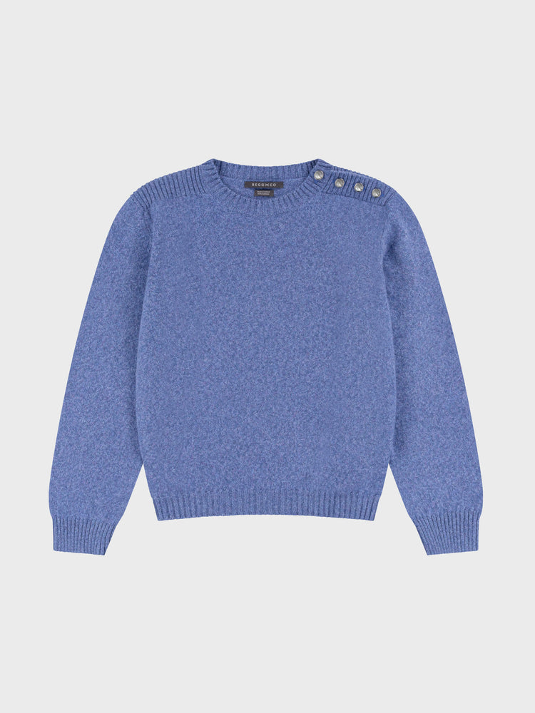 denim blue cashmere crew neck sweater with pearl button shoulder details on a grey background