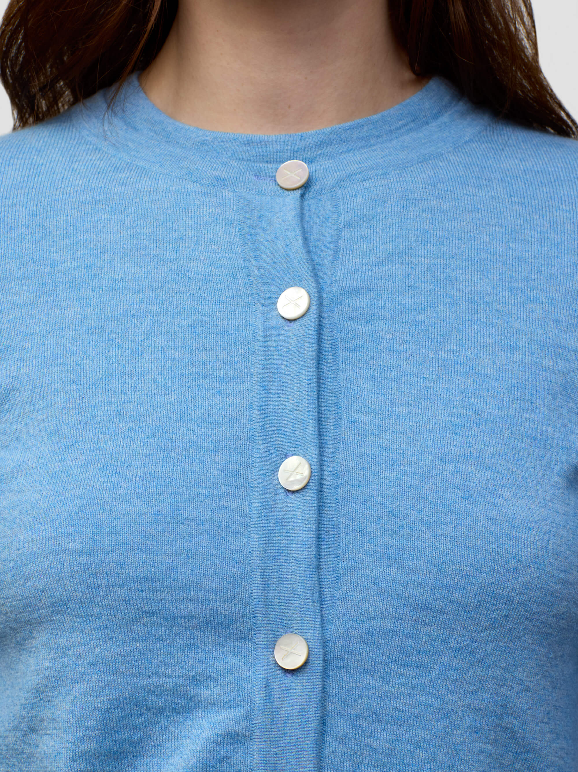 Close-up of a blue cashmere cardigan with buttons on a plain background