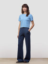 Woman wearing a light blue cashmere tshirt and dark blue cashmere pants on a plain background