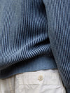 detail of a blue and navy ribbed cashmere cardigan with white shorts