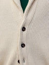 button detail of a man wearing a natural colour ribbed cashmere cardigan over a green tshirt 