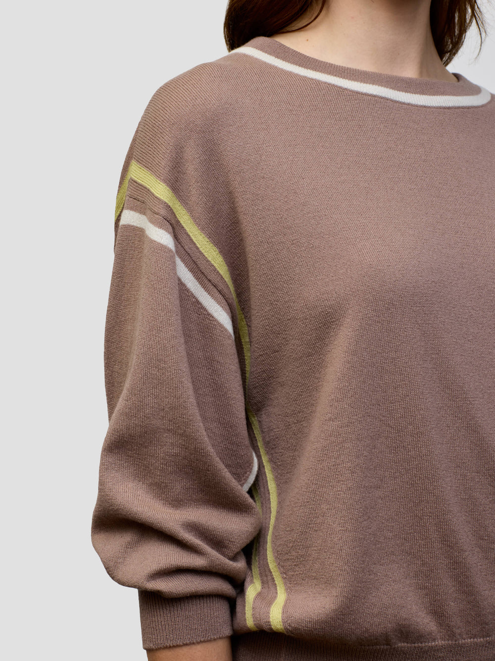 Woman wearing a brown cashmere loungeset with white and yellow stripes on a plain background