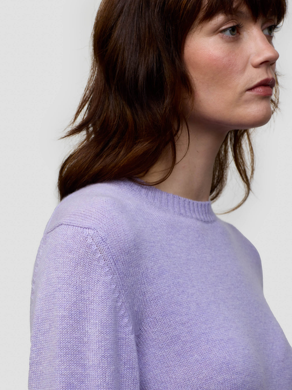 Woman wearing a light purple cashmere sweater against a plain background