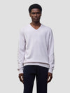 man wearing a light pink cashmere v-neck sweater and navy trousers on a grey background