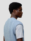 man wearing an arran cable knit blue vest over a grey tshirt on a grey background