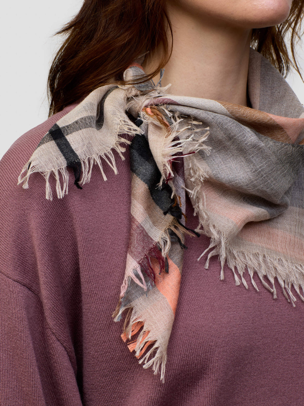 woman wearing a pink cashmere sweater  beige patterned scarf on a grey background