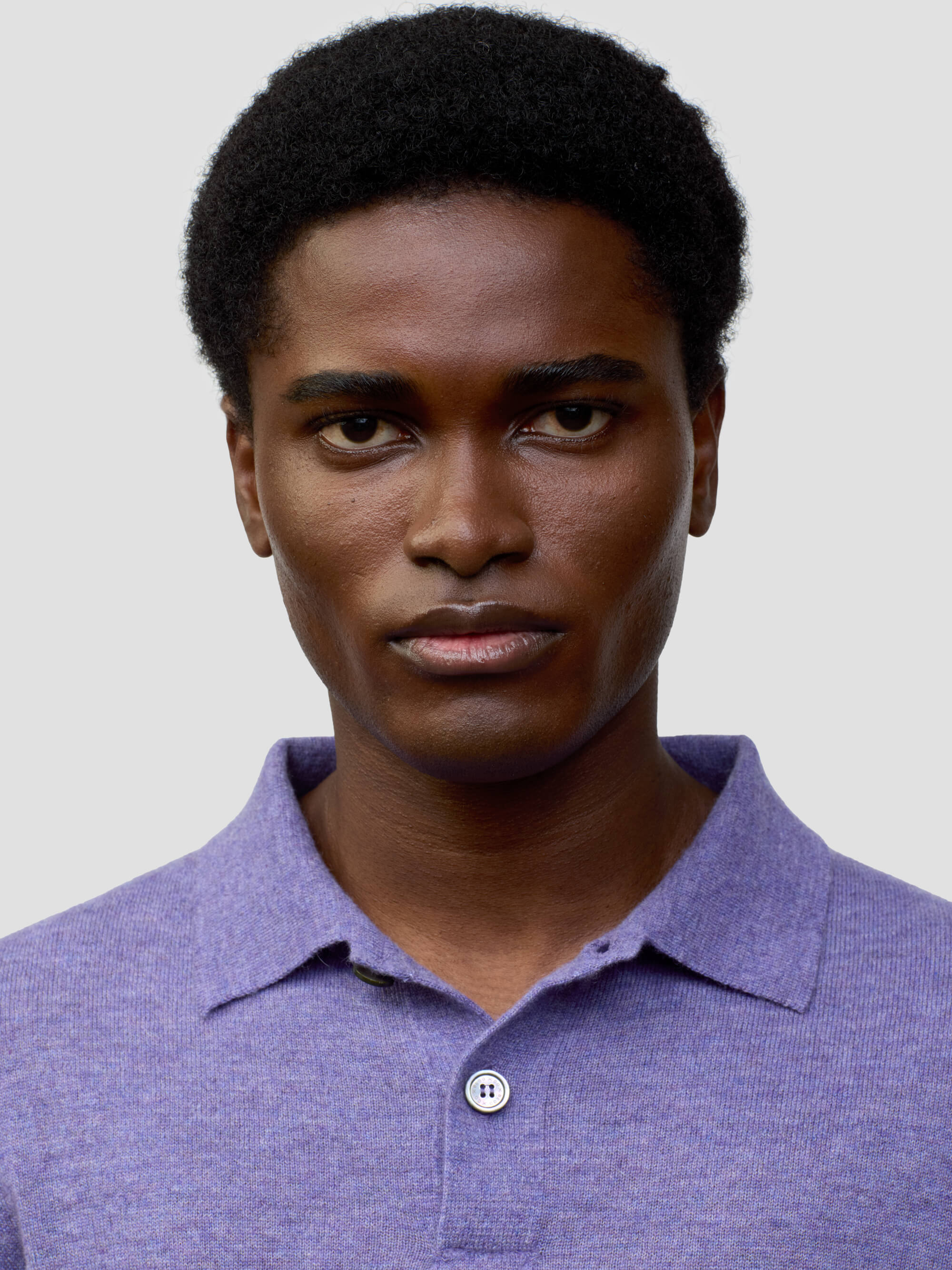 close up of a man wearing a short sleeve cashmere polo on a grey background