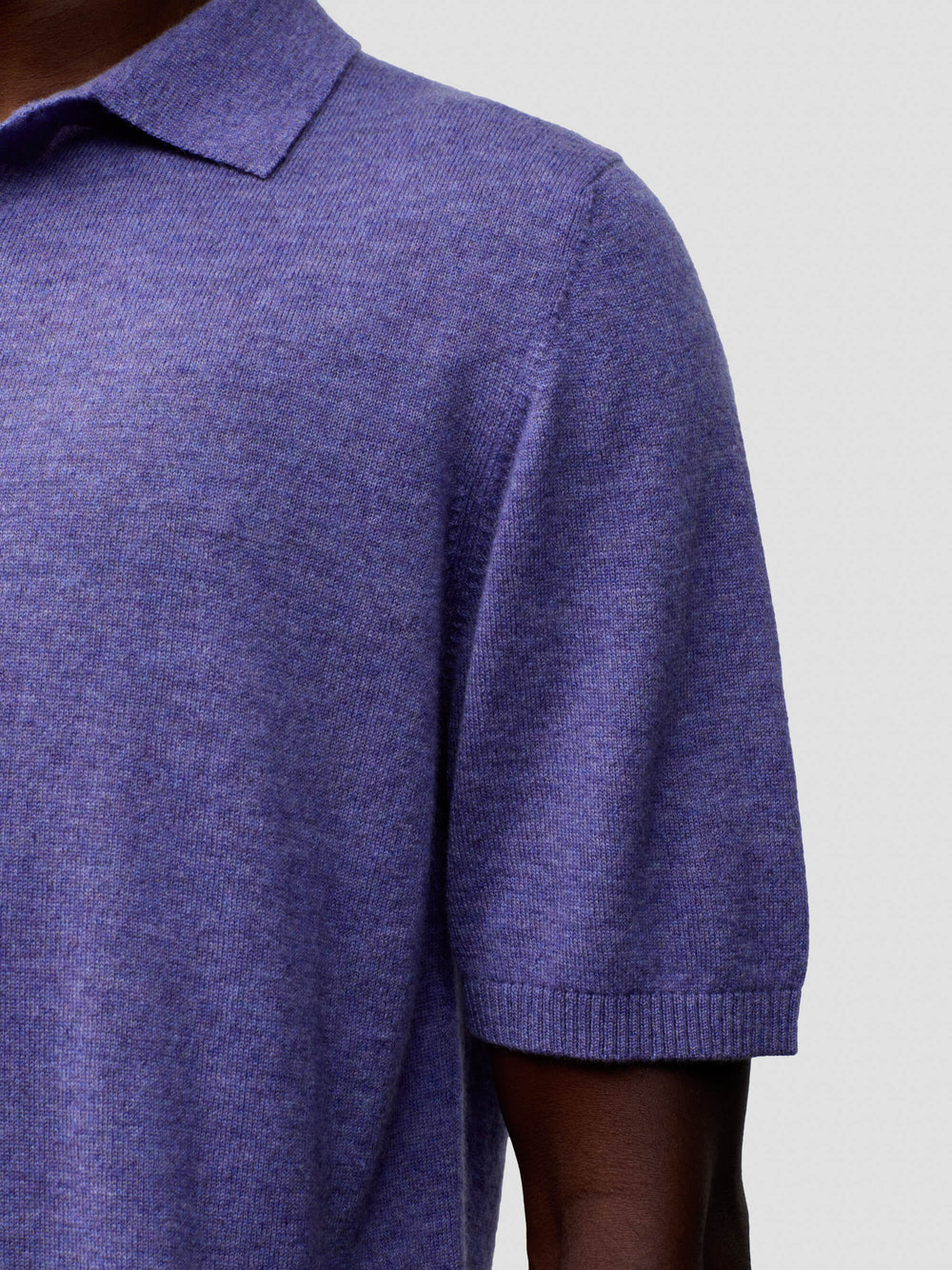 sleeve detail of a man wearing a short sleeve cashmere polo on a grey background