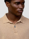 collar and button detail of a man wearing beige cashmere polo on a grey background