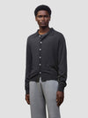 Person wearing a dark gray button-up cashmere cardigan over a gray sweater with light gray pants on a white background