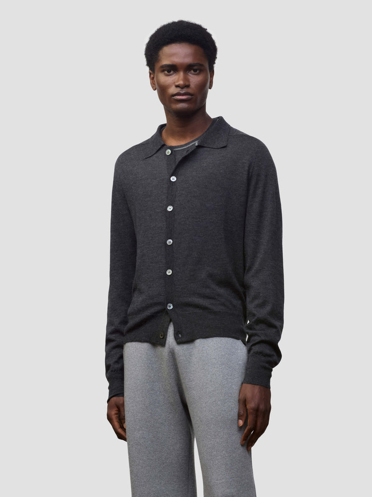 Person wearing a dark gray button-up cashmere cardigan over a gray sweater with light gray pants on a white background