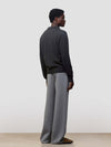 Person wearing a dark gray button-up cashmere cardigan over a gray sweater with light gray pants on a white background