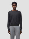 Person wearing a dark gray cashmere sweater and light gray cashmere pants on a plain background