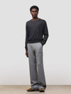 Person wearing a dark gray cashmere sweater and light gray cashmere pants on a plain background