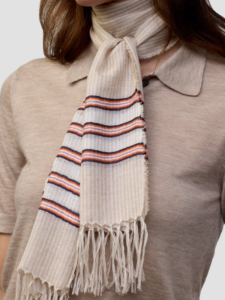 woman wearing a beige cashmere poloshirt with beige and pink striped scarf on a grey background