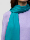 women wearing a lilac cashmere sweater and teal scarf on a grey background