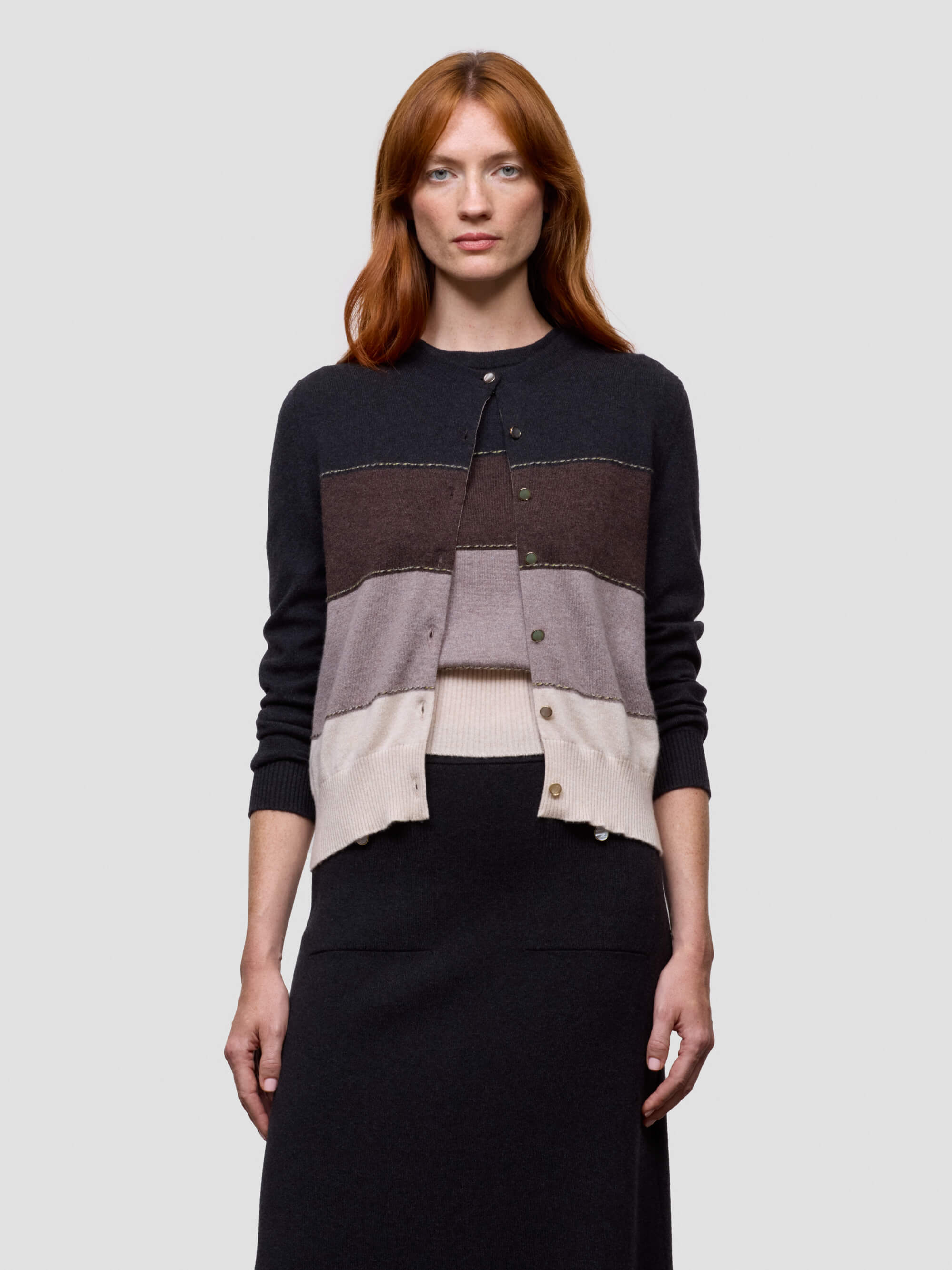 Woman wearing a color-blocked cashmere sweater with a plain background