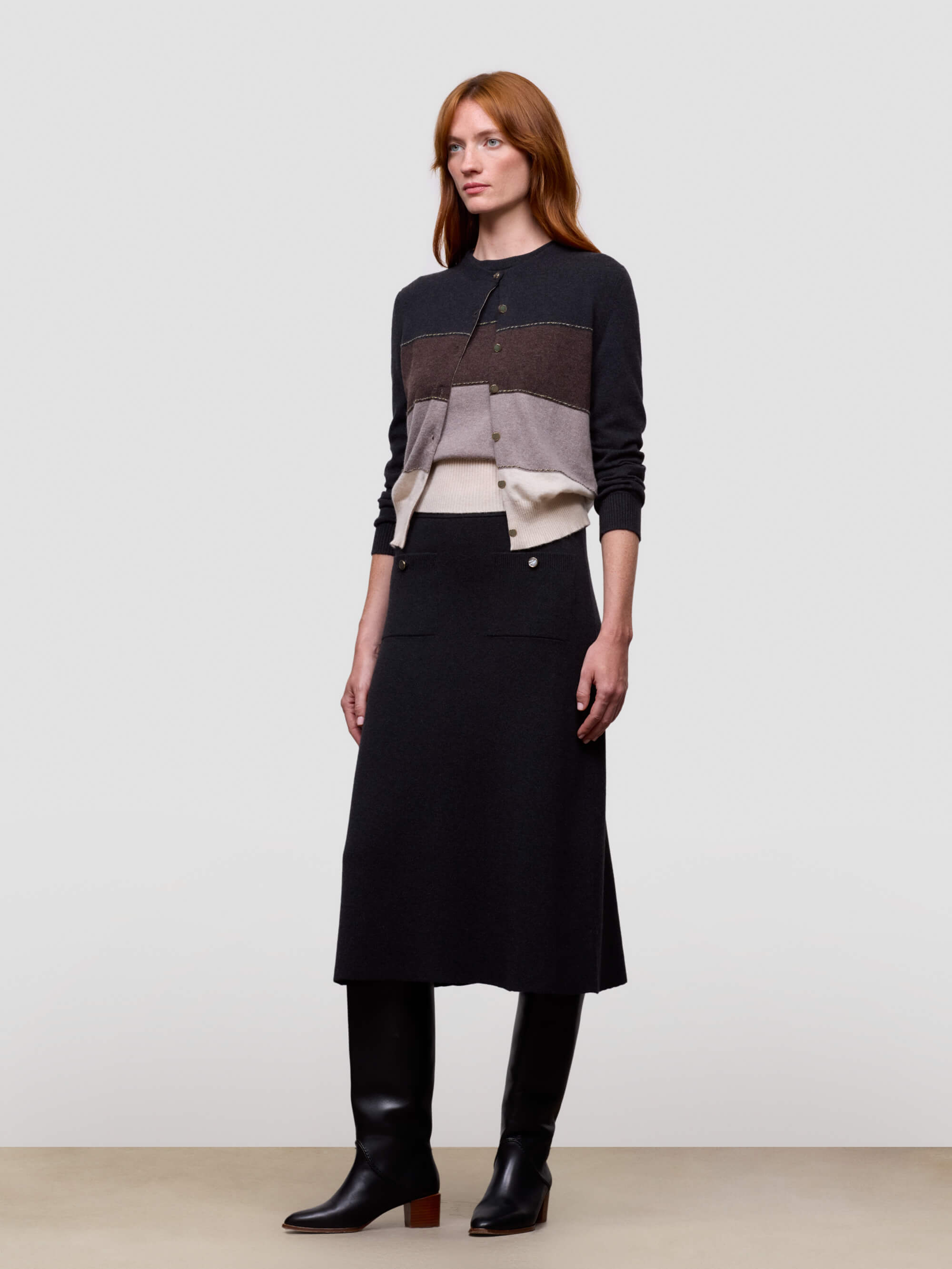 Woman wearing a black and gray cashmere sweater with a long black skirt on a white background