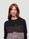 Woman wearing a black, brown, and gray color-blocked cashmere sweater on a light gray background
