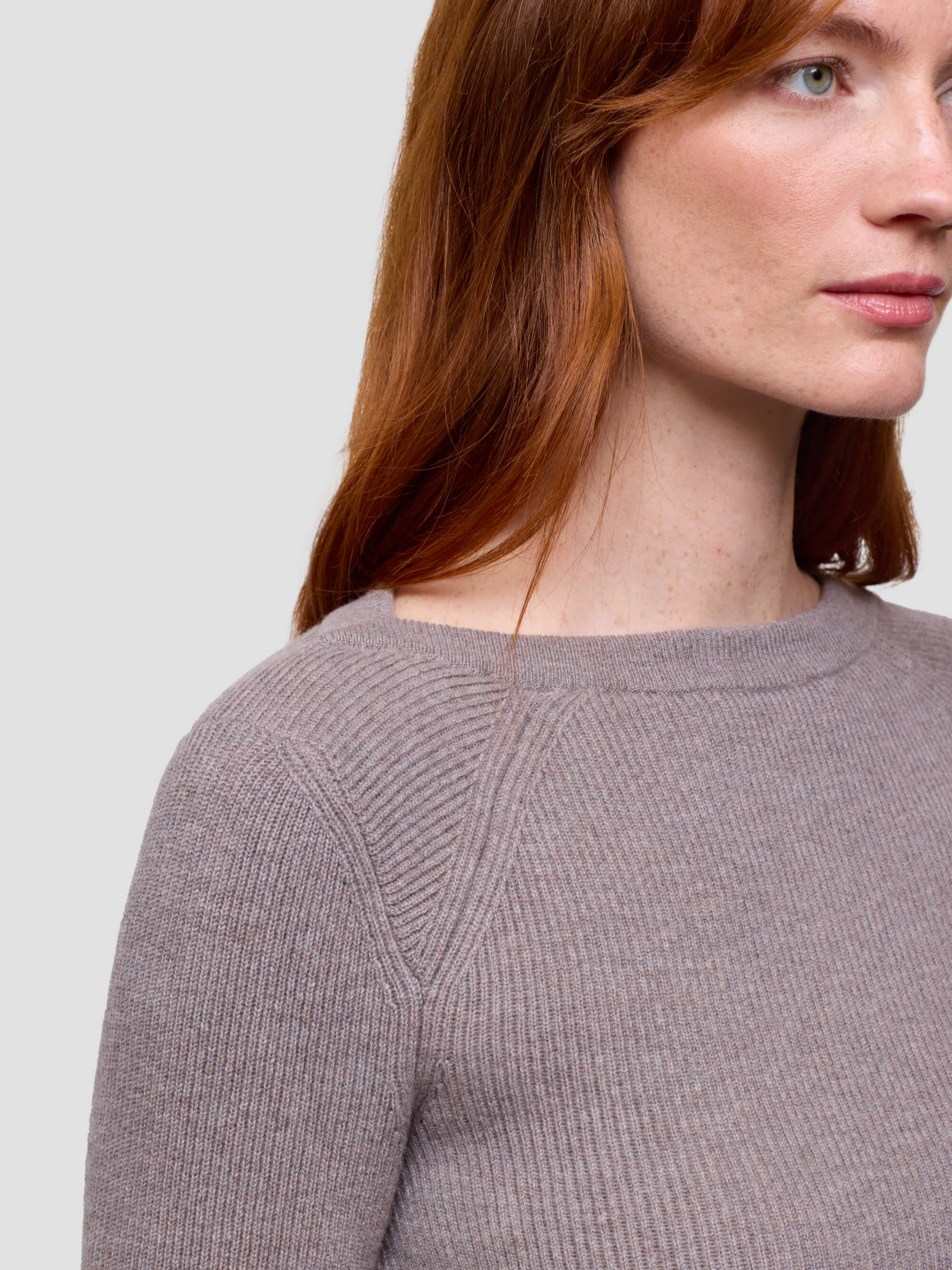 Woman wearing a gray cashmere sweater on a light gray background