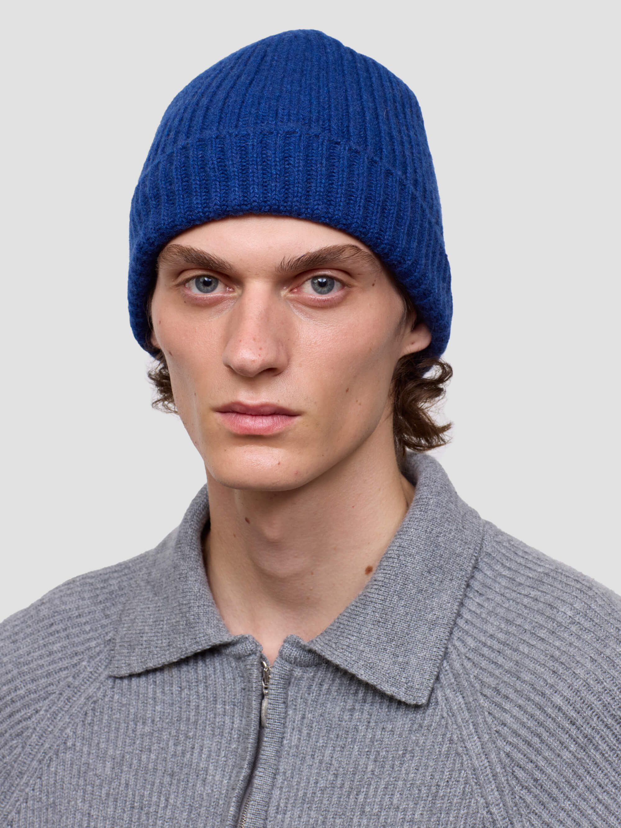 man wearing a blue ribbed cashmere beanie and grey ribbed zip sweater
