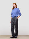 woman wearing a blue cashmere sweater and gray pants on a plain background