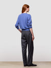 Woman wearing a blue cashmere sweater and dark pants against a white background