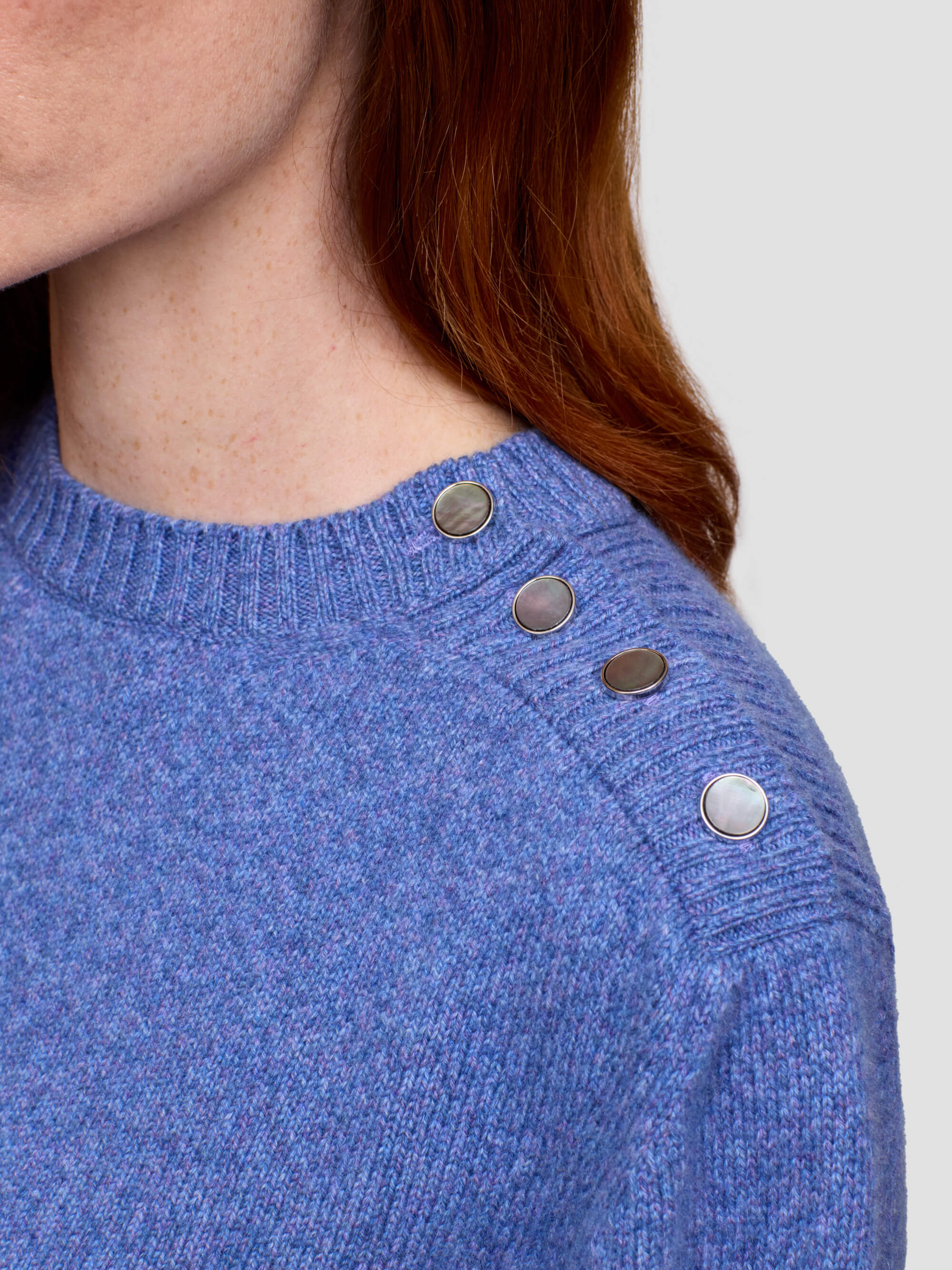 pearl button detail of a blue cashmere sweater