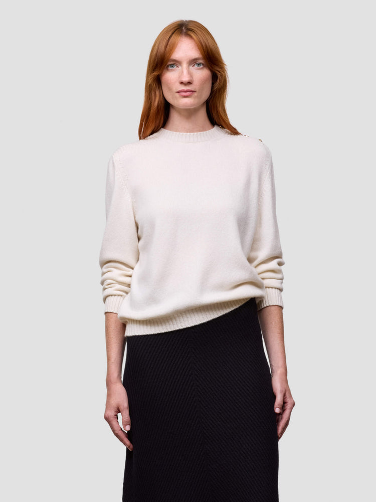 Woman wearing a white cashmere sweater and black skirt on a light gray background