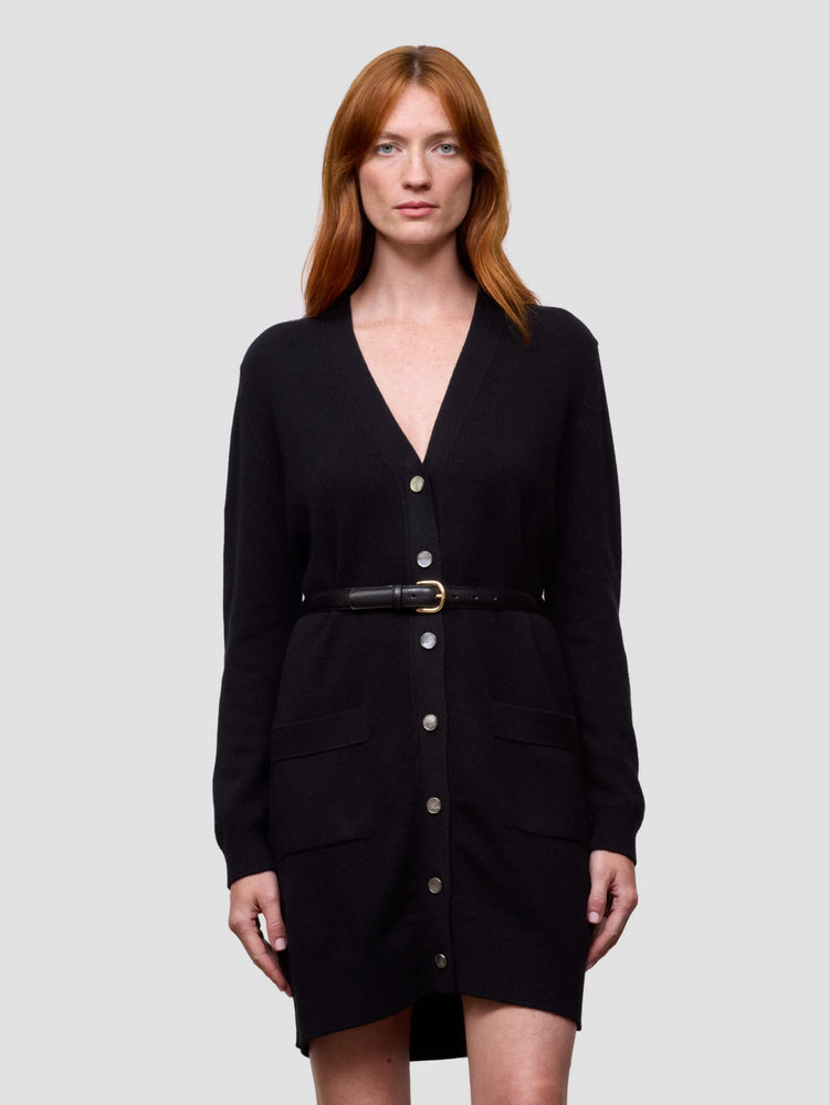 Woman wearing a black cashmere cardigan dress with a belt on a light gray background